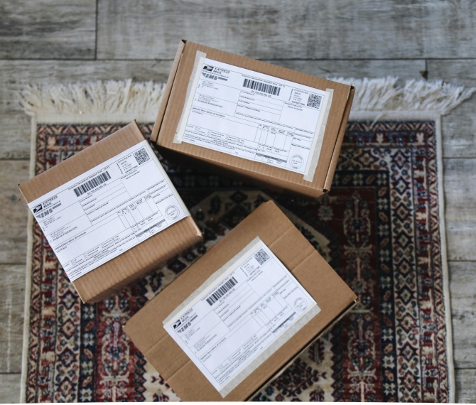 Three labeled delivery boxes placed on a decorative rug over a wooden floor.